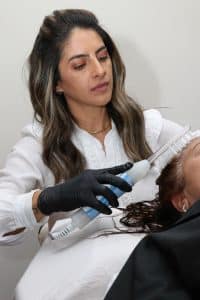 Vall Carvalho, cabeleireira e terapeuta capilar, durante procedimento no couro cabeludo em S&atilde;o Carlos